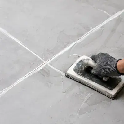 Fresh grout being worked into tile joints with a float